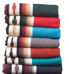 a stack of colorful towels sitting on top of a wooden table next to a white wall