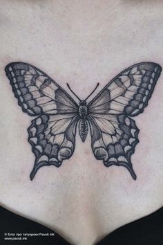 a woman's chest with a butterfly tattoo on the top and bottom part of her stomach