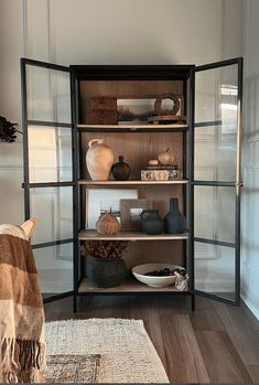 a shelf with vases and other items on it in the corner of a room