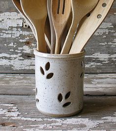 wooden utensils in a white cup with holes on the sides and spoons inside