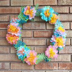 a wreath made out of paper flowers on a brick wall