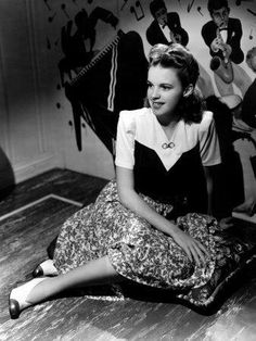 a woman sitting on the floor in front of a wall with musical notes painted on it