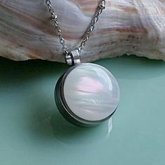 Very pretty opalescent keepsake locket necklace. Consider filling with memorial ashes, a lock of hair or pet fur, or dried special occasion flowers. Fill it with anything meaningful.  *Your keepsake is nicely displayed through the back glass of this 3/4" round locket.  *Lovely opal colors including shades of irridescent pinks and pale greens. Colors appear more vibrant or opaque depending on the lighting. *All stainless-steel base and chain make it nice for everyday wear. No worries about tarnis Lock Of Hair, Round Locket, Urn Jewelry, Memory Locket, Urn Necklace, Hair Locks, Urn Necklaces, Human Ashes, Opal Color