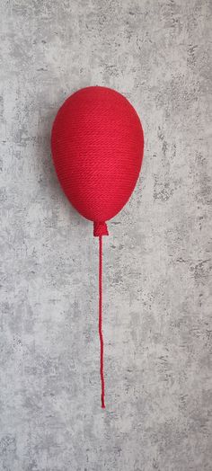 a red balloon hanging from the side of a wall with a string attached to it