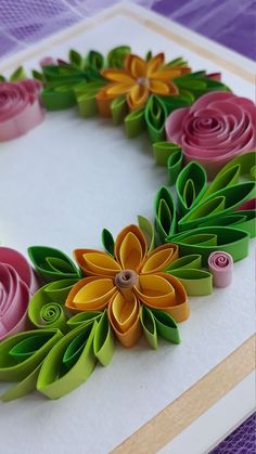 paper flowers are arranged in the shape of a wreath on top of a card board