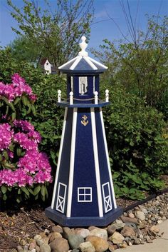 a small blue and white clock tower next to flowers