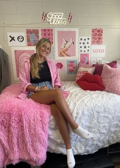 a woman sitting on top of a bed in a room with pink furniture and decorations