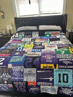 a bed covered in lots of t - shirts next to a window