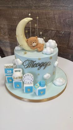 a teddy bear is sitting on top of a blue cake with stars and moon decorations