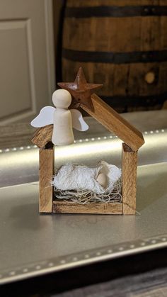 a small wooden nativity scene with a star on the top and white wool inside