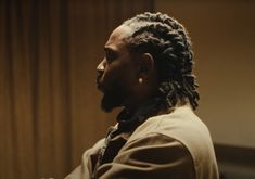 a man with dreadlocks is standing in front of a curtain and looking off into the distance