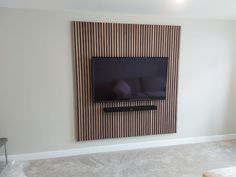 a flat screen tv mounted to the side of a wall in a room with carpeted flooring