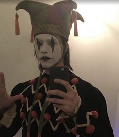 a man dressed as a clown taking a selfie in front of a mirror with his cell phone