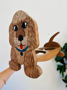 a wooden dog ornament hanging on a wall next to a potted plant