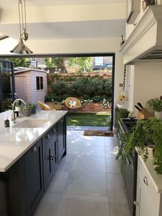 a kitchen with an open glass door leading to the back yard and garden area in front of it