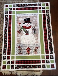 a quilted snowman with a red hat and scarf on it's chest