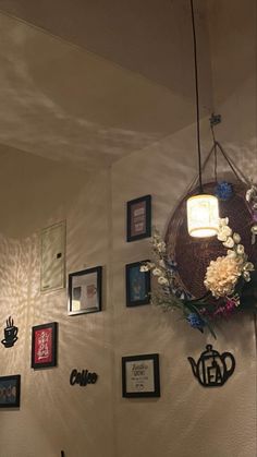 a wall with pictures and flowers hanging from it's sides, along with a lamp