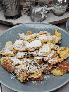 a blue plate topped with powdered sugar covered pastries