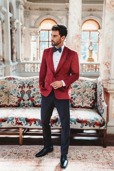 a man in a red tuxedo standing next to a couch