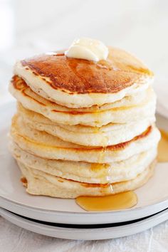 a stack of pancakes on a plate with butter and syrup drizzled on top