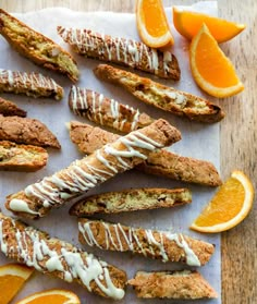 an assortment of oranges and pastries on a cutting board with icing drizzled