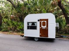 a small white trailer parked on the side of a road with trees in the background