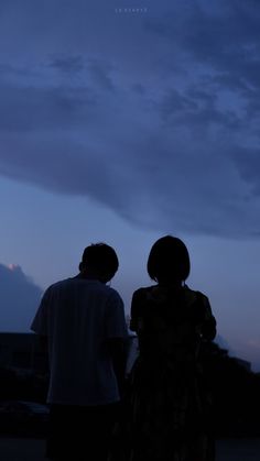 two people standing in front of a dark sky at night with the moon behind them