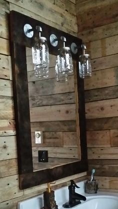 a bathroom sink sitting under a mirror next to a wooden wall