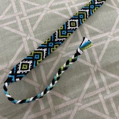 a close up of a lanyard on a bed with a blue and green design