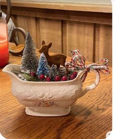 a ceramic bowl filled with christmas decorations and deer figurines on top of a wooden table