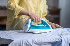 a woman ironing fabric with an electric iron