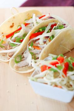 three tacos sitting on top of a wooden table