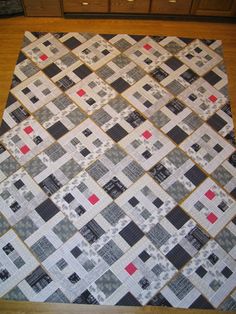 a close up of a patchwork quilt on a wooden floor with drawers in the background