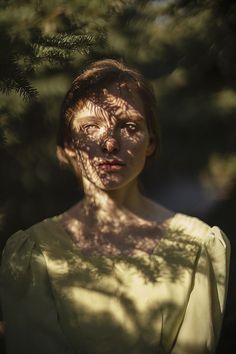 a woman with freckles on her face standing under a tree