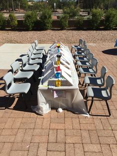 a long table covered in plastic chairs on a brick patio