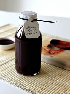 a bottle of syrup sitting on top of a bamboo mat next to a bowl of sauce