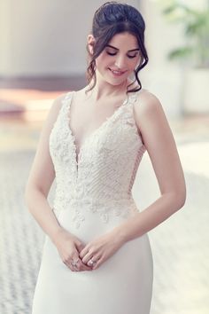 a woman in a white wedding dress is holding her hands on her waist and smiling