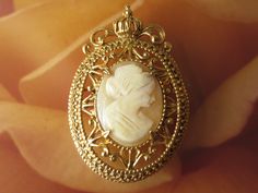 A beautiful signed Florenza cameo brooch, real carved shell portrait in an ornate goldtone setting with a crown at the very top. The backside has an attached bail if wanting to wear as a pendant by adding a necklace chain.  The brooch is 1 1/2 by 2 inch.  Mark:  Florenza In wonderful condition and ready to wear or give as a gift.  To see all the jewelry in my Etsy shop, go to my home page here ~ www.etsy.com/shop/darsjewelrybox Elegant Gold Cameo Brooch, Cameo Pendant Brooch For Wedding, Cameo Pendant Brooches For Wedding, Gold Cameo Brooch For Wedding, Formal Gold Cameo Brooches, Formal Gold Cameo Brooch, Gold Cameo Medallion Brooch, Gold Cameo Medallion Brooches, Shell Portrait