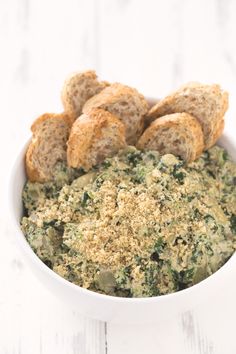 a white bowl filled with spinach and bread crumbs on top of a table