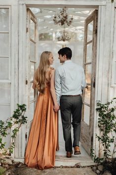 a man and woman standing in front of an open door looking into each other's eyes