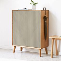 a wooden cabinet with an umbrella on it next to a small side table and chair