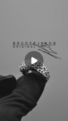 a man wearing a black jacket and silver ring with the words bruderjakob on it