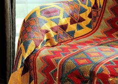 a large colorful blanket sitting on top of a couch next to a window sill