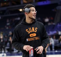 a man wearing a sun's basketball hoodie holding a water bottle