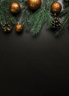 christmas decorations on black background with pine cones and fir branches in gold glittered balls