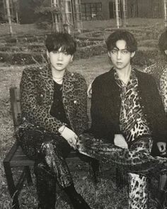 three people sitting on a bench wearing animal print clothes and ties, one person is holding a snake