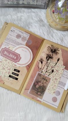 an open book with flowers on it sitting on top of a white furnishing