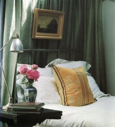 a bedroom with a bed, nightstand and flowers on the end table in front of it