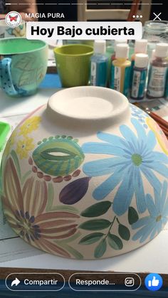 a vase with flowers painted on it is sitting on a table next to other items