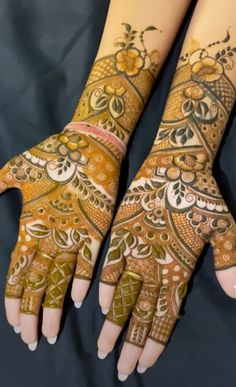 two hands with henna tattoos on them, one is showing off the intricate design